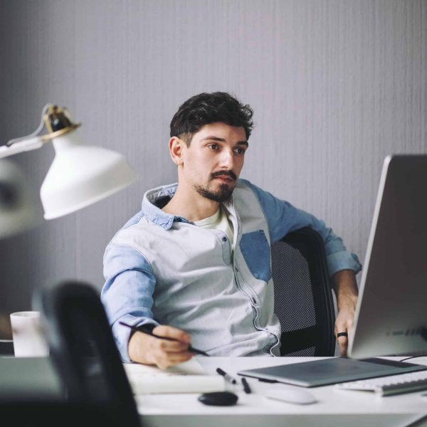 A man sitting at his desk looking at the computer screen.
